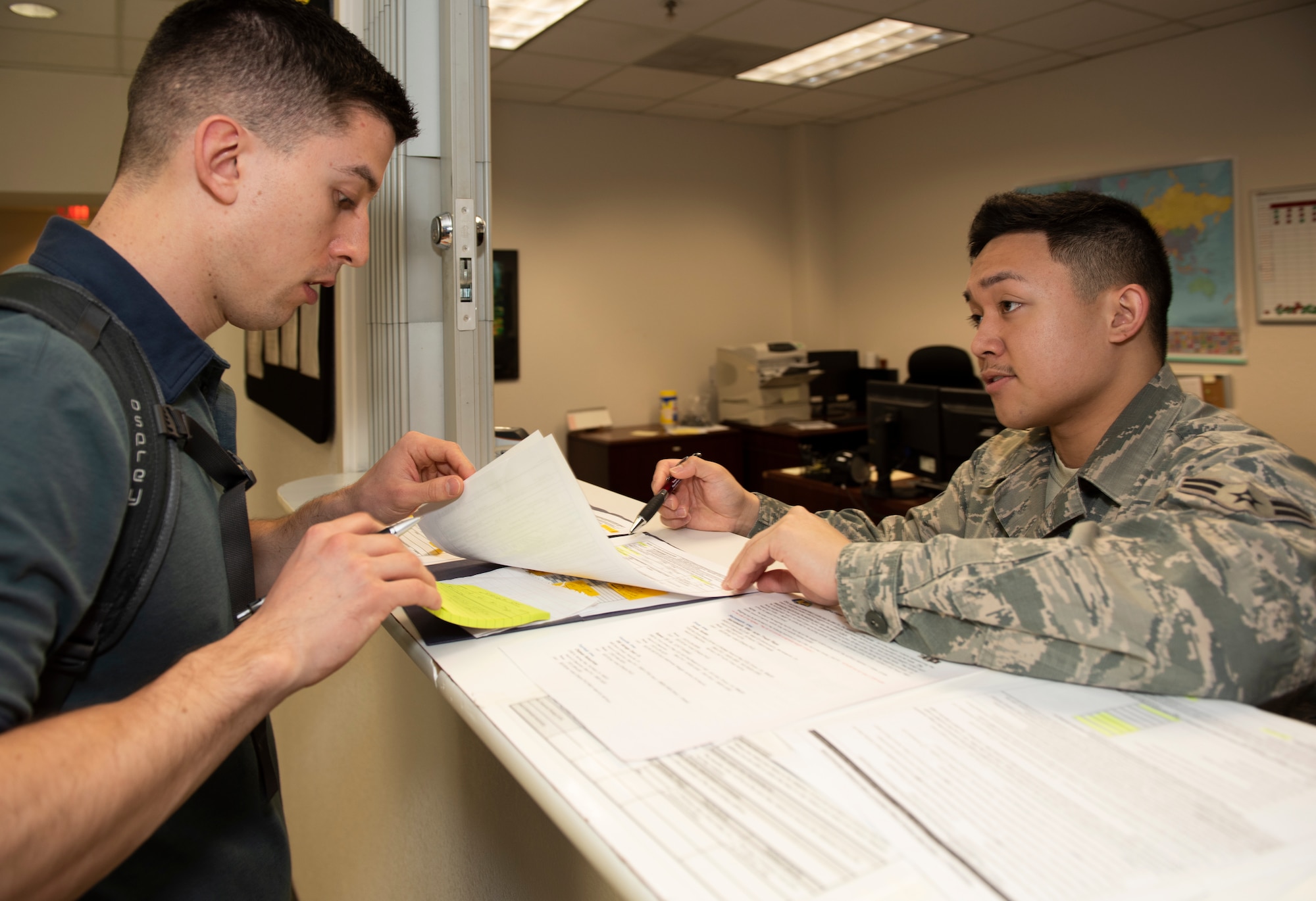 U.S. Air Force 1st Lt. John Walters, left, 340th Flying Training Squadron, receives advice from Airman 1st Class Bernard Alamoro, 60th Aerial Port Squadron, on filling out paper work while at the Transportation Management Office, April 8, 2019, at Travis Air Force Base, California. The TMO is responsible for ensuring the efficient transport of service members’ household goods. (U.S. Air Force photo by Heide Couch)