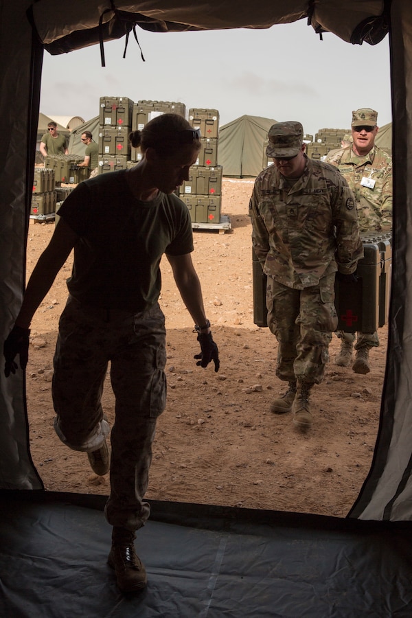 U.S. Navy Lt. Cmdr. Christine DeForest, an emergency medicine physician with Special Purpose Marine Air-Ground Task Force-Crisis Response-Africa 19.1, Marine Forces Europe and Africa, directs Staff Sgt. Bryant Beasley, a gun chief with 1st Battalion, 148th Field Artillery Regiment, 116th Cavalry Brigade Combat Team, Idaho Army National Guard, and Sgt. 1st Class Donald Robertson, a platoon sergeant with 1-148th FAR, where to put a can in a medical tent during exercise African Lion 2019, in Tan Tan, Morocco, March 25, 2019. African Lion is an annual, multinational, joint-force exercise designed to improve interoperability and mutual understanding of each nation’s tactics, techniques and procedures while demonstrating a strong partnership between nation’s militaries. (U.S. Marine Corps photo by Cpl. Tessa D. Watts)