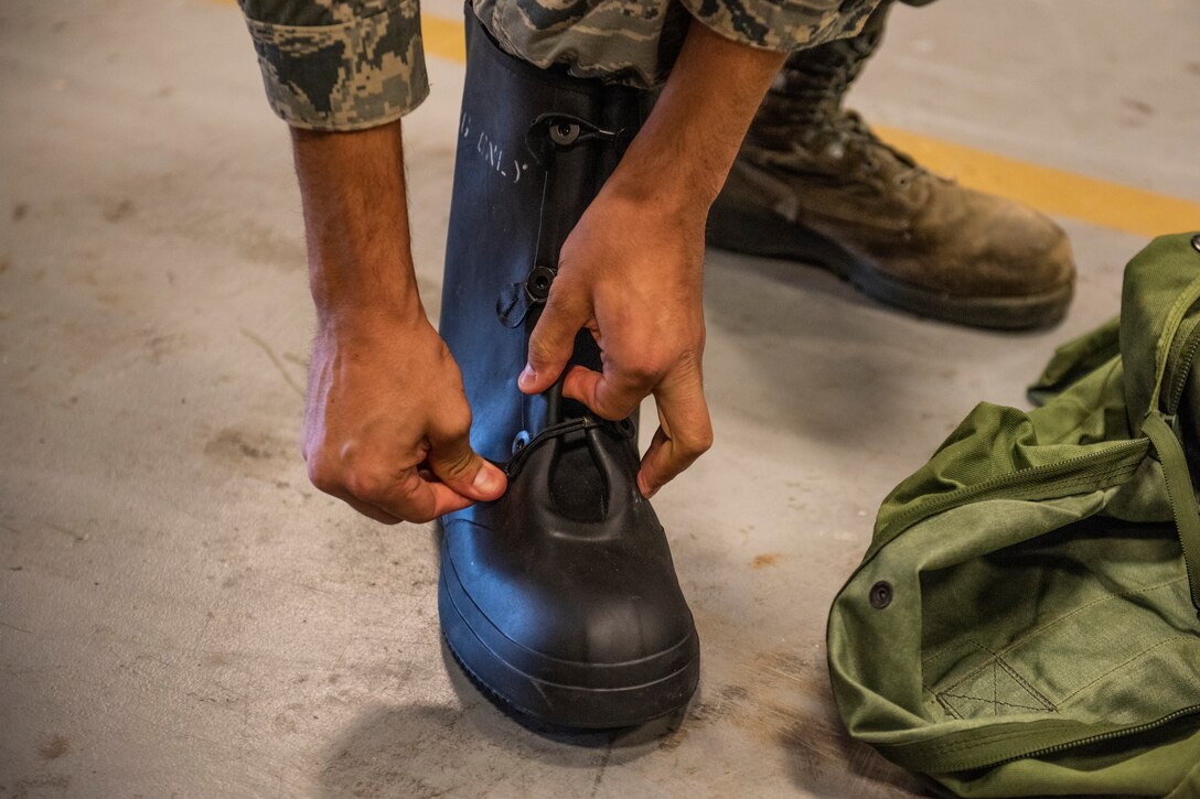 An Airman tries on a pair of boots April, 2, 2019 at Moody Air Force Base, Ga. From April 15-19, 2019, Moody executed a base-wide exercise that required players to function at a high operations tempo in a chemical, biological, radioactive and nuclear environment to meet Chief of Staff of the Air Force and the Commander of Air Combat Command’s intent for readiness. (U.S. Air Force photo by Airman 1st Class Joseph P. Leveille)