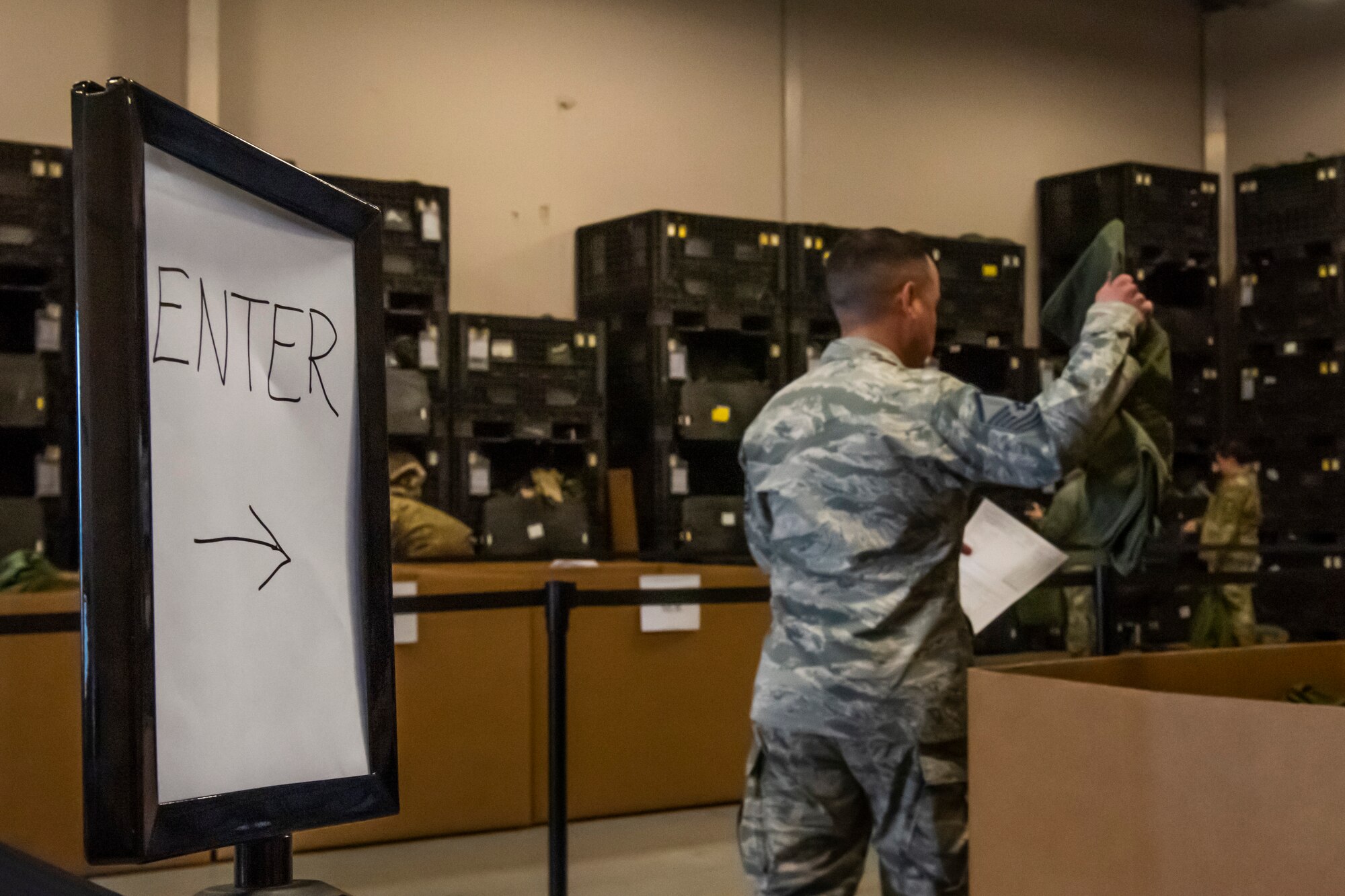 An Airman picks up a bag for his MOPP gear April 2, 2019, at Moody Air Force Base, Ga. From April 15-19, 2019, Moody executed a base-wide exercise that required players to function at a high operations tempo in a chemical, biological, radioactive and nuclear environment to meet Chief of Staff of the Air Force and the Commander of Air Combat Command’s intent for readiness. (U.S. Air Force photo by Airman 1st Class Joseph P. Leveille)