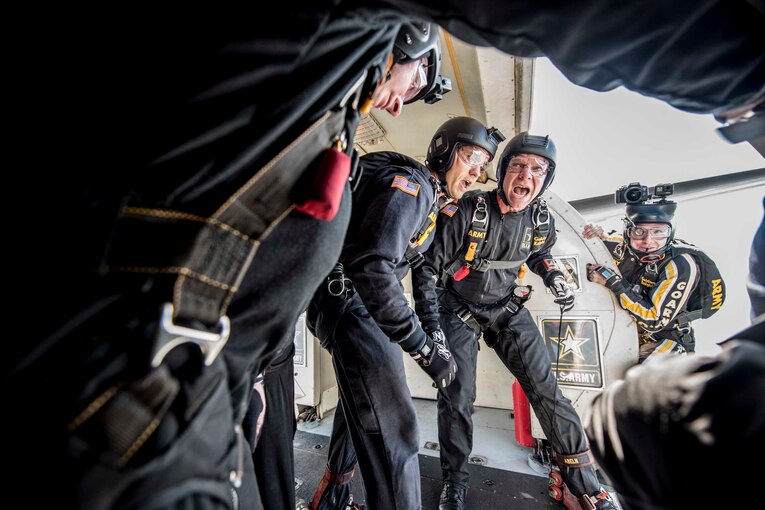 Four soldiers stand at the door of a aircraft preparing to jump.