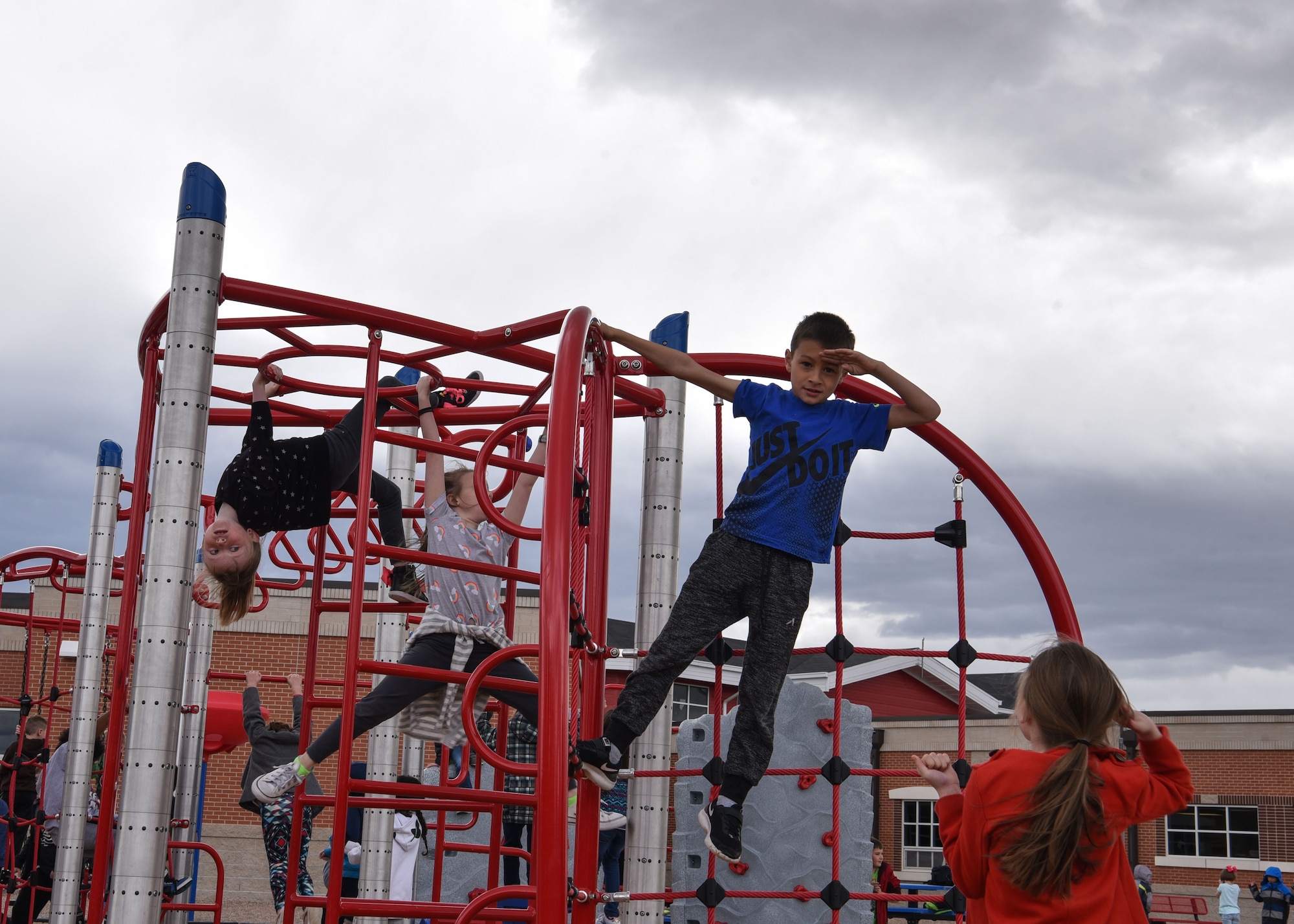 Reagan salutes a classmate from the top of a jungle gym, April 15, 2019, in Cheyenne, Wyo. While his understanding of the military is limited he knows what his mom is doing is important and he is proud that she is in the military. (U.S. Air Force photo by Airman 1st Class Braydon Williams)