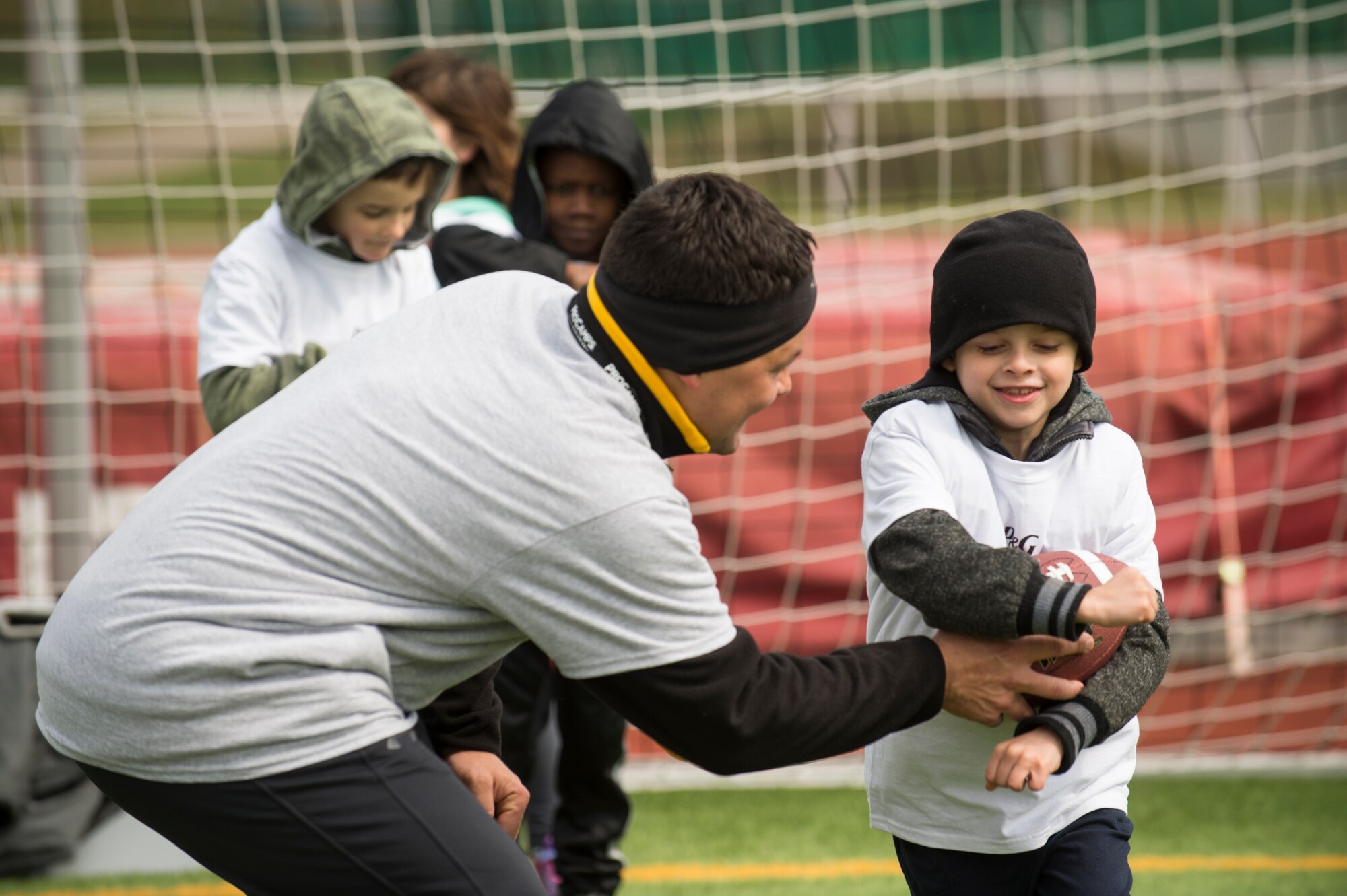 A volunteer coach hands the ball off to an Alejandro Villanueva football camp attendee during offensive drills at Kaiserslautern High School on Vogelweh Military Complex, Germany, April 13, 2019. Volunteer coaches from around the Kaiserslautern Military Community coached young football players on offensive and defensive drills, along with seven-on-seven games. (U.S. Air Force photo by Staff Sgt. Jonathan Bass)