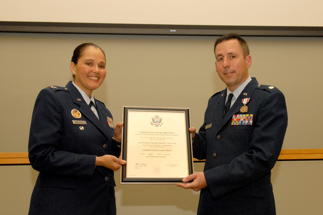 Air Force Col. Mary Ann Garbowski, Air Force Medical Operations Agency Medical Logistics director, left, and Lt. Col. Roger Willis, DLA Troop Support Medical supply chain’s Institutional Customer Facing Division chief, right, pose with Willis’ retirement certificate during a ceremony at DLA Troop Support April 12, 2019 in Philadelphia.