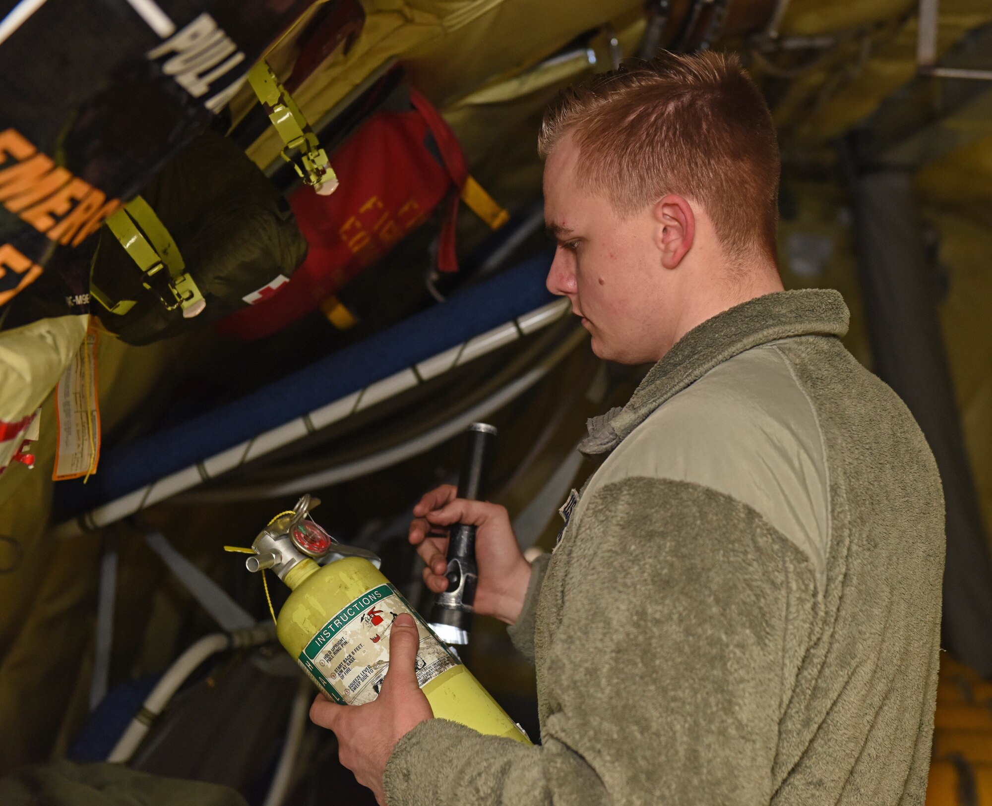 U.S. Air Force Airman 1st Class Brenden Hurston, 100th Aircraft Maintenance Squadron crew chief, checks the pressure gauge on a fire extinguisher during the preflight inspection of a KC-135 Stratotanker at RAF Mildenhall, England, March 5, 2019. Preflight inspections are conducted after recovering a KC-135 to ensure the aircraft are ready to fly again. (U.S. Air Force photo by Senior Airman Luke Milano)