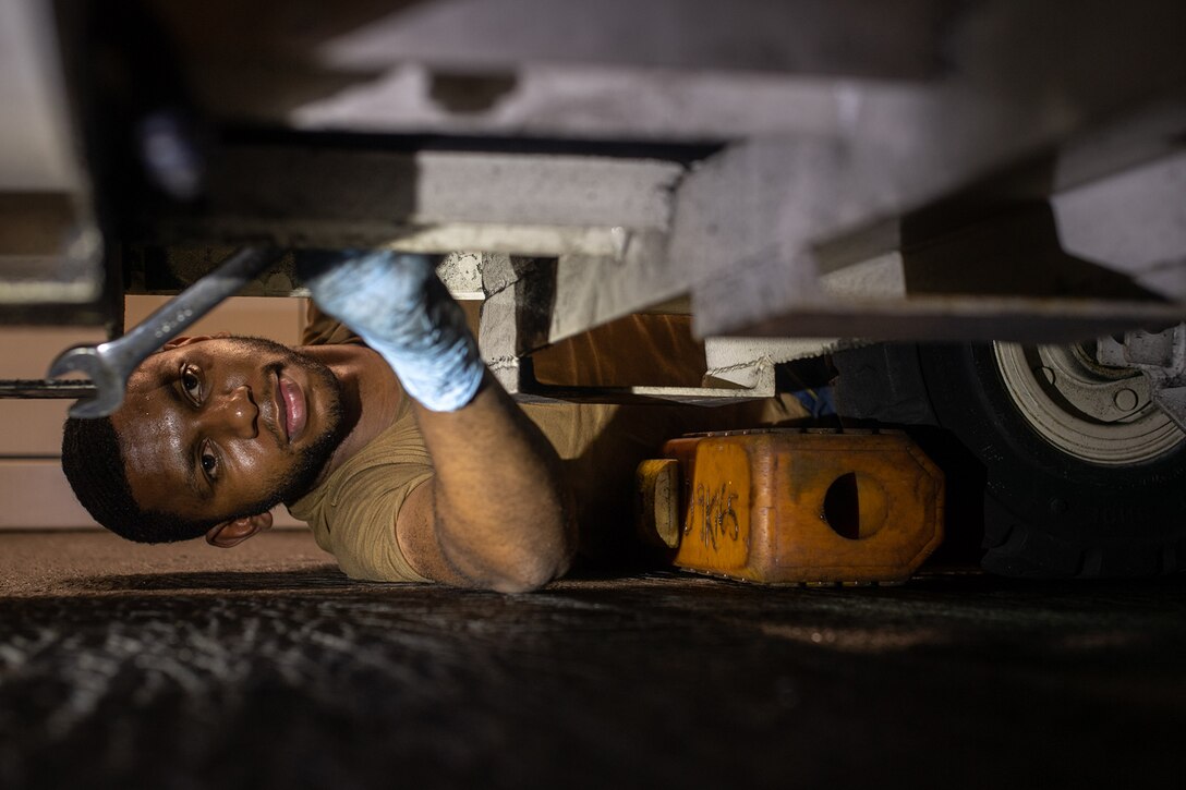 A sailor removes a bolt from a generator.