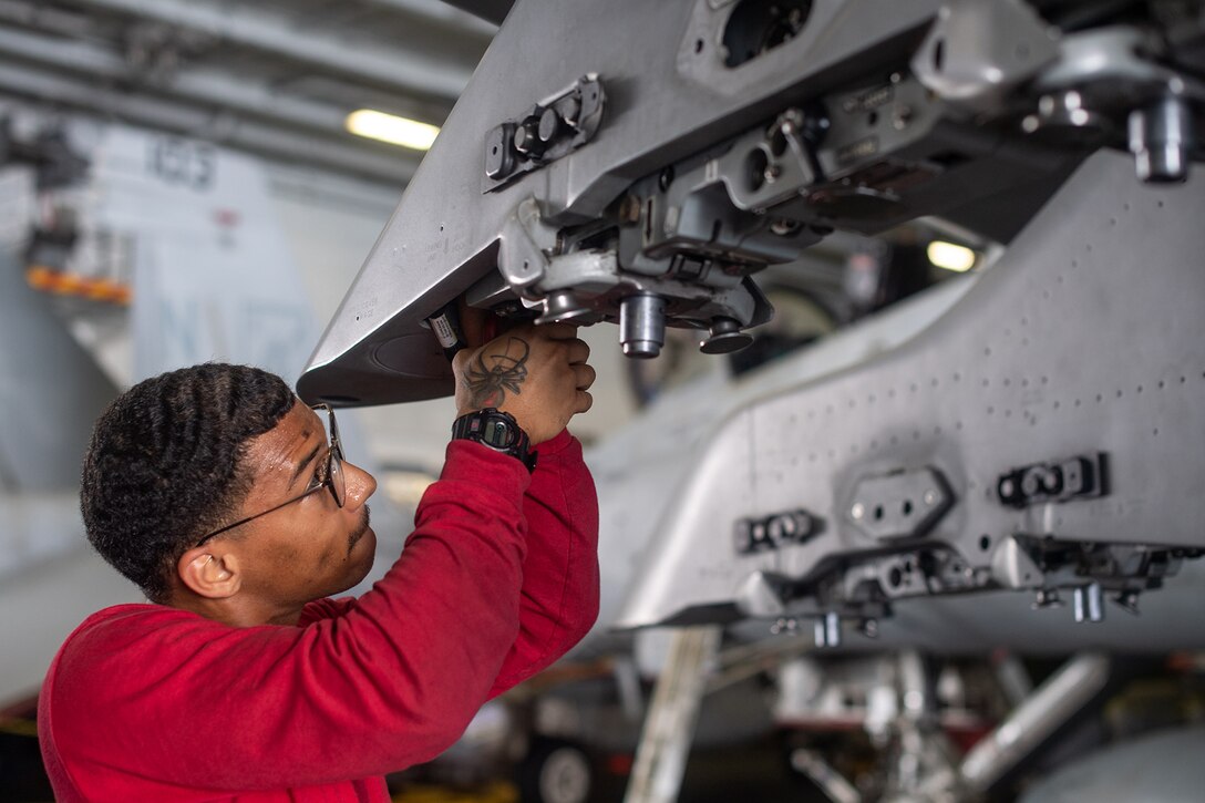 A sailor replaces a unit on an aircraft.