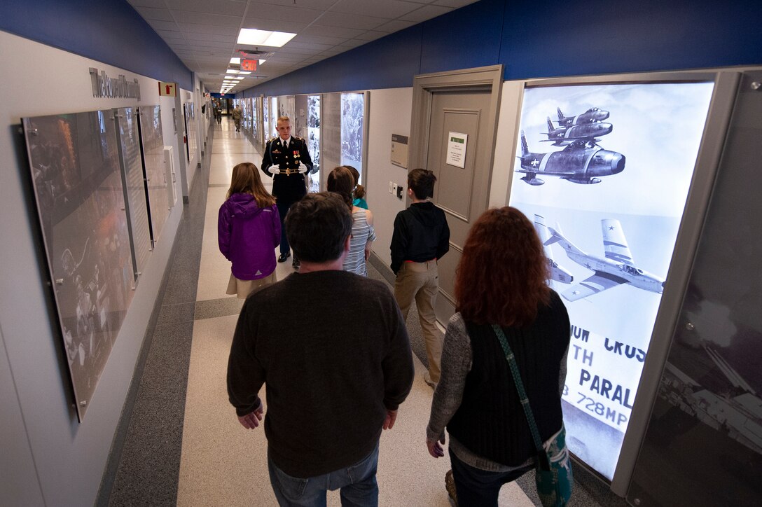 A soldier stands in the distance in a long Pentagon hallway as a tour group follows him.
