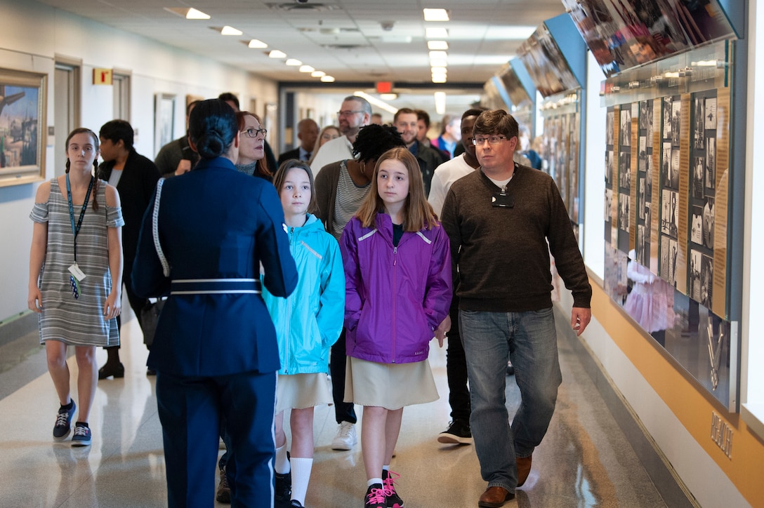 Airman walks backward as she talks to a tour group in a Pentagon hallway.