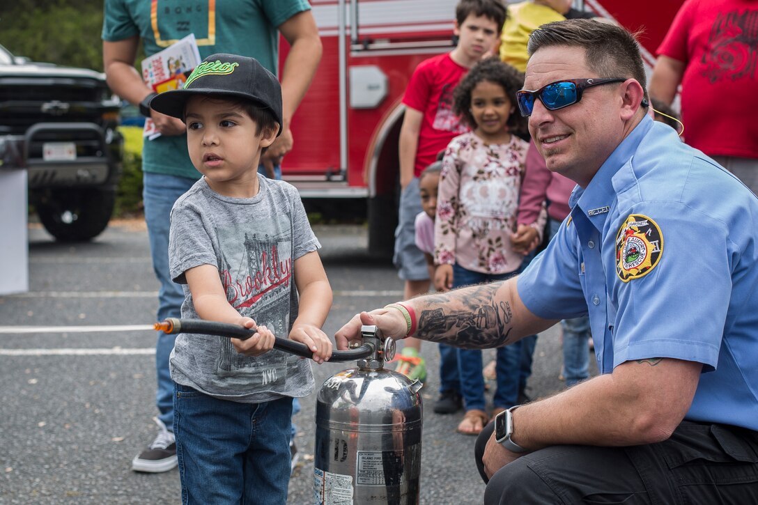 A Beaufort Fire Department member helps a child with a fire extinguisher drill at KidFest in Beaufort, April 6. KidFest is held to raise awareness for Child Abuse Prevention Month while also celebrating the Month of the Military Child with the local community.