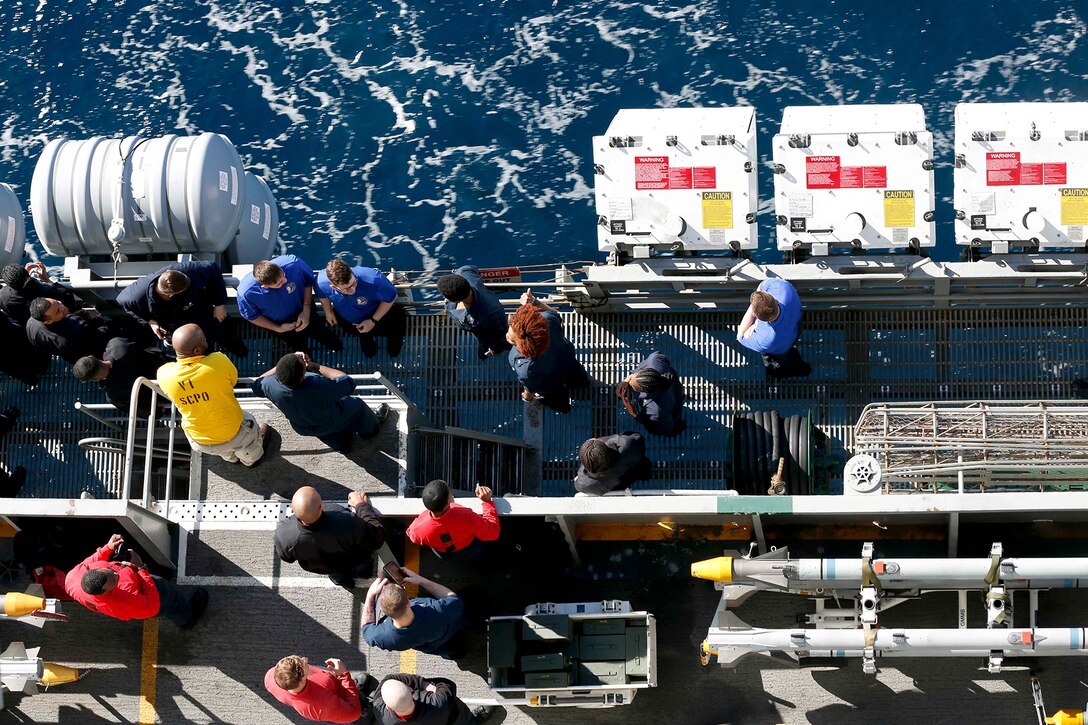 Sailors look out from a ship.