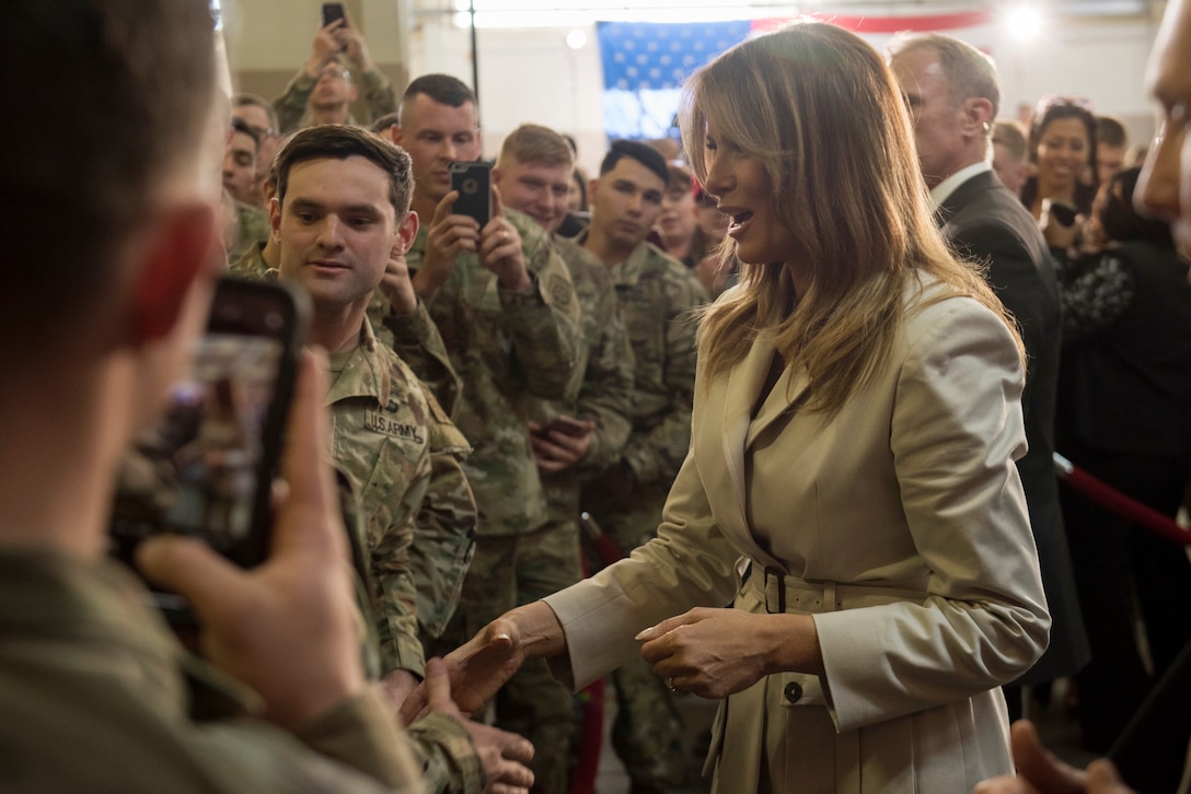 Melania Trump shakes hands while surrounded by a group of soldiers.