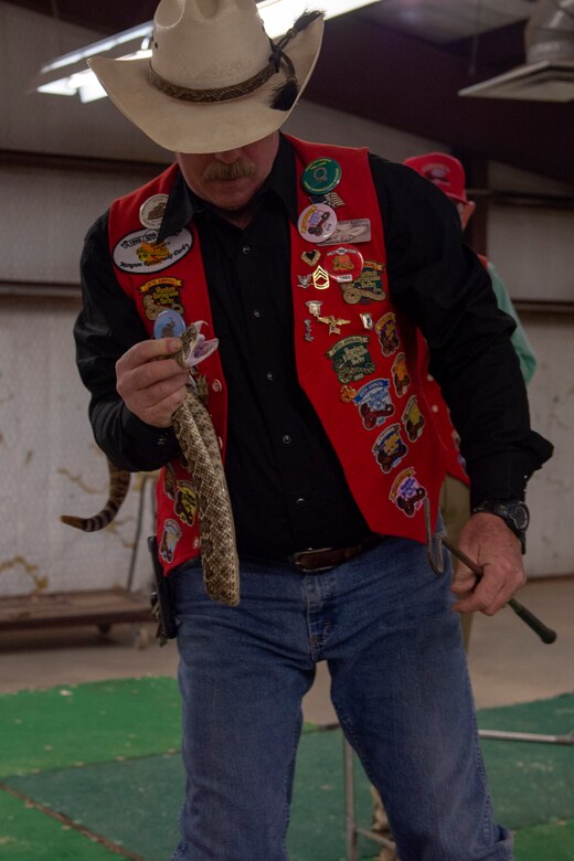 A member of the Shortgrass Rattlesnake Association holds a rattlesnake up before members of the 97th Air Mobility Wing, April 15, 2019, at Altus, Okla. Each Committee of 100 dinner is different and meant to showcase an aspect of the local culture in Altus.
