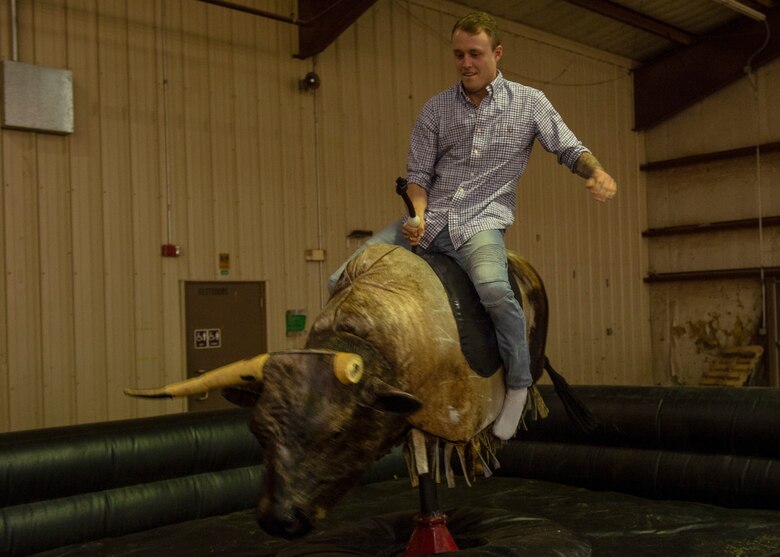 A student from the 97th Training Squadron rides a mechanical bull during the quarterly Committee of 100 dinner, April 15, 2019, at Altus, Okla. More than 300 base members attended the event, showcasing a strong bond between the local community and the 97th Air Mobility Wing.