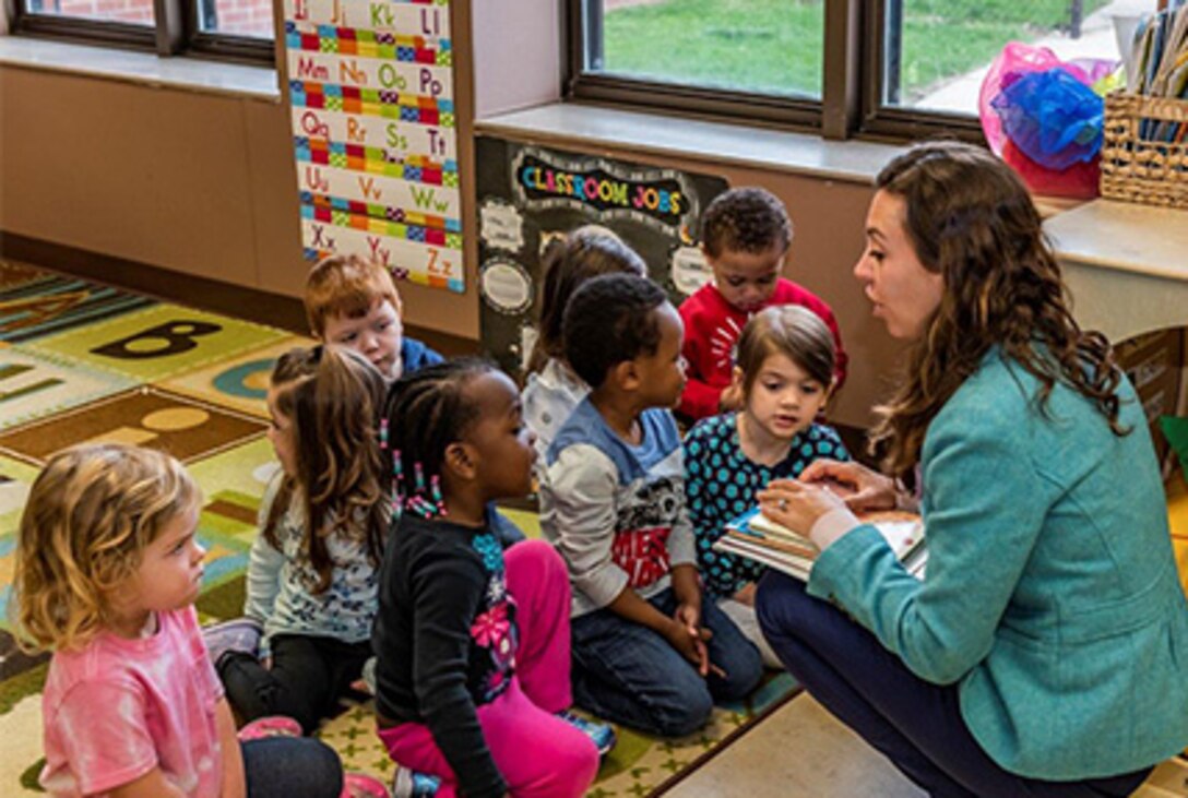 Children gather around on classroom rug surrounding guest speaker