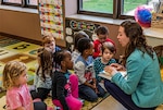 Children gather around on classroom rug surrounding guest speaker