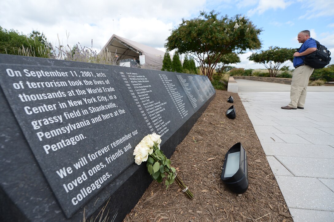 A tourist stands in front of a placard at the National 9/11 Pentagon Memorial.