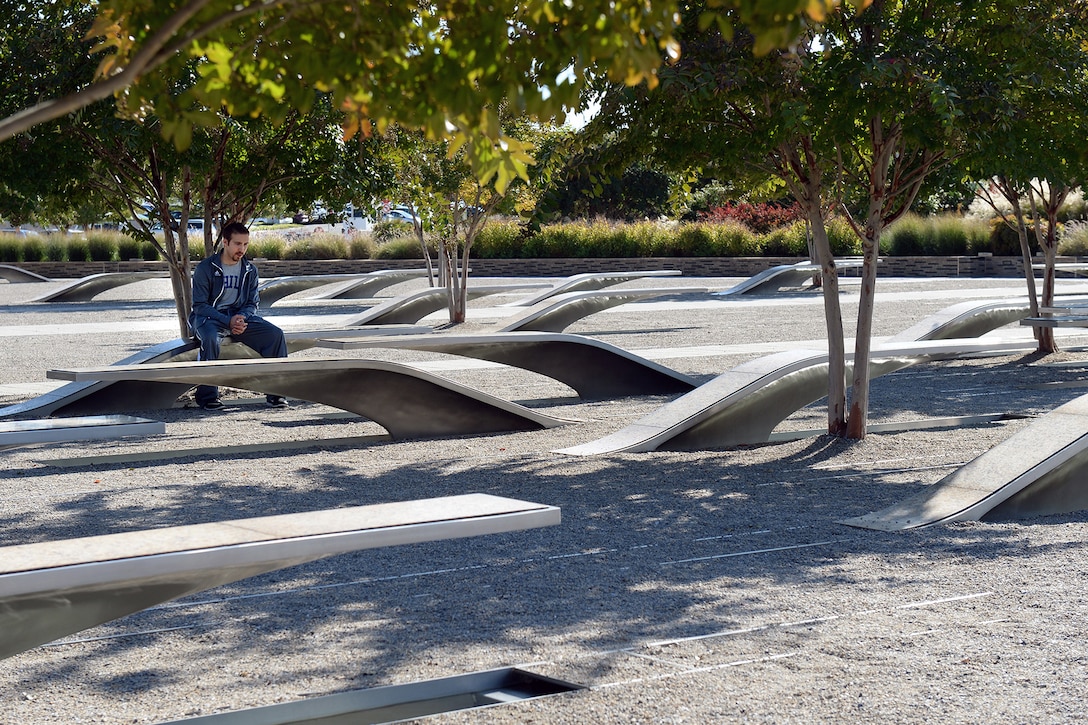 A man sits at one bench in a field of benches.