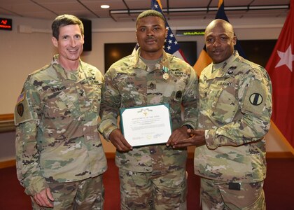 U.S. Army Staff Sgt. Brandon Scarbrough (center), aircraft structural repair instructor, Charlie Company, 2-210 Battalion, 128th Aviation Brigade, receives his award for Fort Eustis’ NCO of the year April 15, 2019. (U.S. Air Force Photo by Senior Amn. Delaney Gonzales)