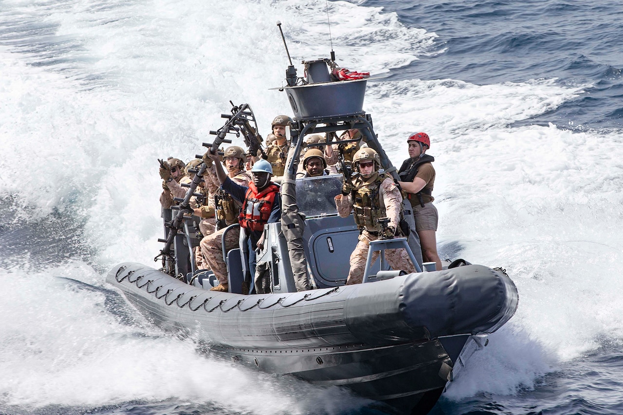 Troops stand in a speeding boat.