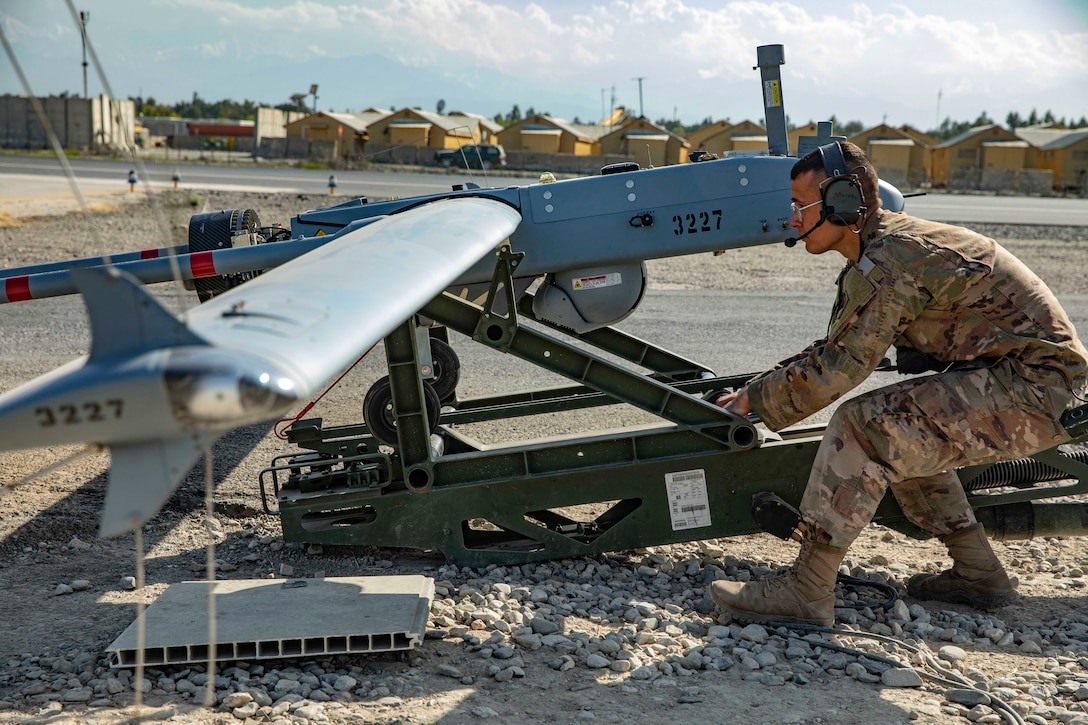 A soldier pulls a small unmanned aircraft.