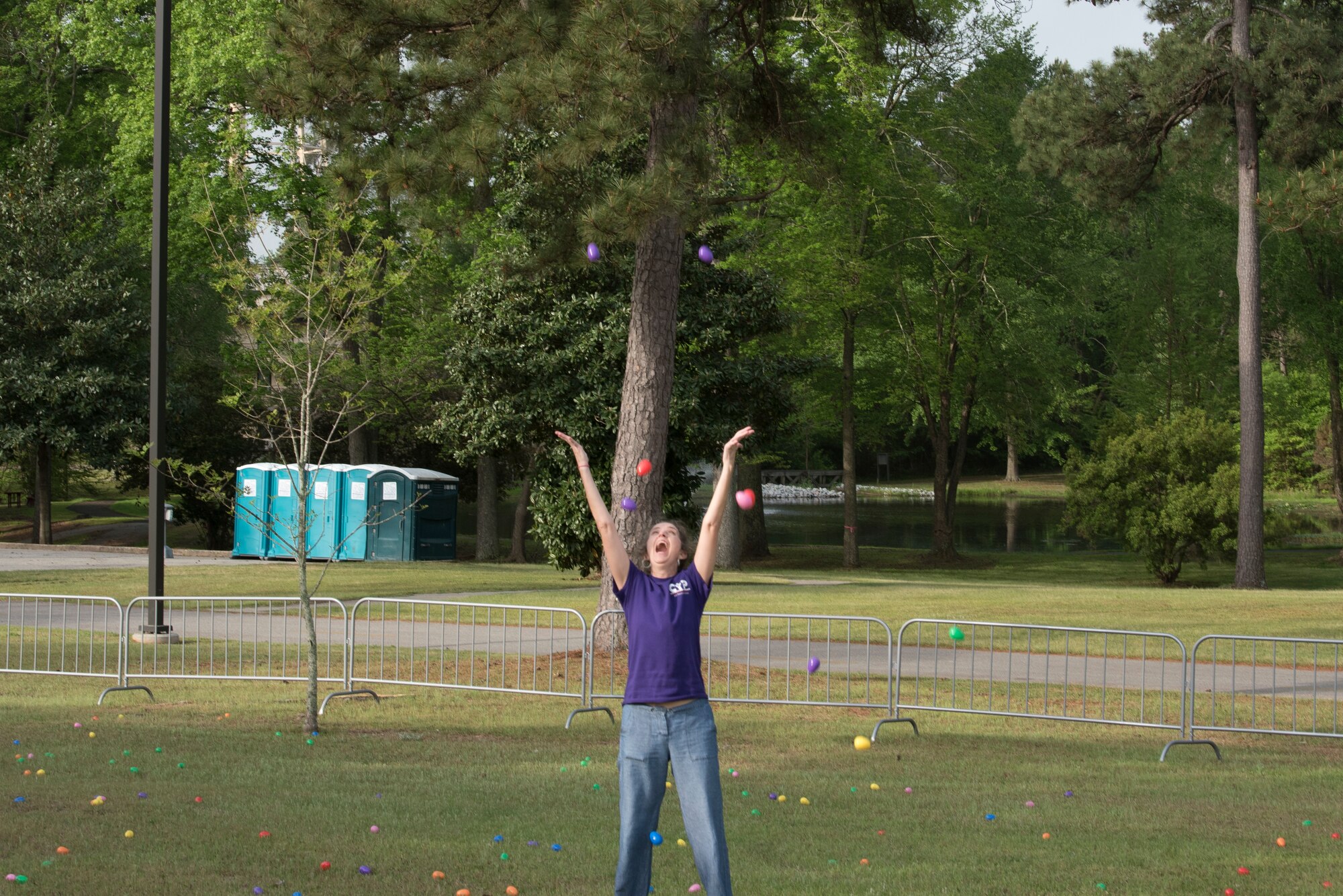 Deborah MacQueen, the 20th Force Support Squadron director of the Child and Youth Program throws Easter eggs in the air to disperse the eggs throughout the fenced in egg hunting area on Shaw Air Force Base, SC, April 13, 2019.