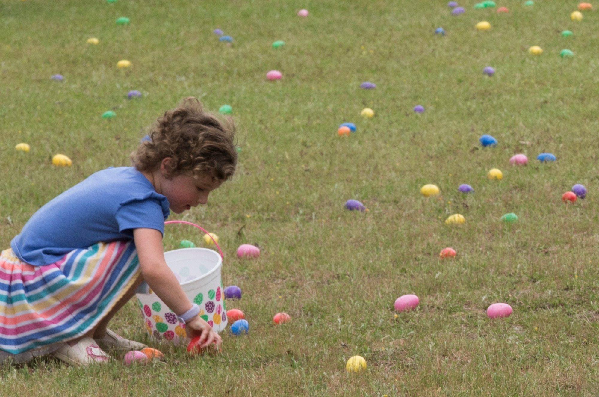 A Team Shaw child picks up an egg during a children's’ Easter egg hunt on Shaw Air Force Base, SC, April 13, 2019.
