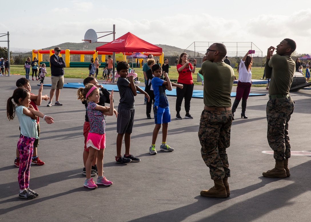 Sgt. Arik C. Myers, an administrative clerk with Headquarters and Headquarters Squadron and Pfc. Demeris M. Scott, a postal clerk with H&HS, conduct cool down stretches after performing a two part circuit course with Del Sur community members in San Diego, April 11. The Marines attended Del Sur Elementary school’s first Annual Health and Fitness Night to inspire students and parents alike to live a healthier lifestyle and form stronger relations with the surrounding community. (U.S. Marine Corps photo by Sgt. Sarah Ralph)