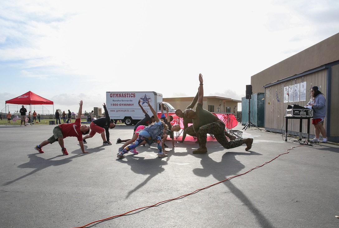 Sgt. Arik C. Myers, an administrative clerk with Headquarters and Headquarters Squadron and Pfc. Demeris M. Scott, a postal clerk with H&HS, conduct a two part circuit course with Del Sur community members in San Diego, April 11. The Marines attended Del Sur Elementary school’s first Annual Health and Fitness Night to inspire students and parents alike to live a healthier lifestyle and form stronger relations with the surrounding community. (U.S. Marine Corps photo by Sgt. Sarah Ralph)