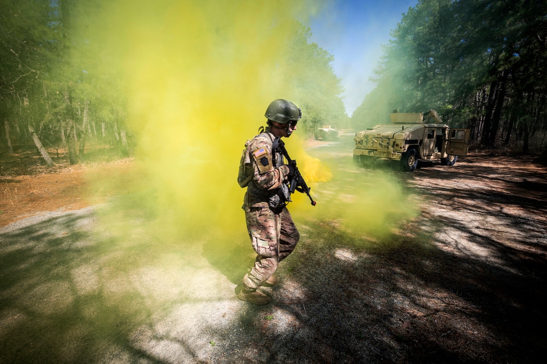A soldier walks through yellow smoke.