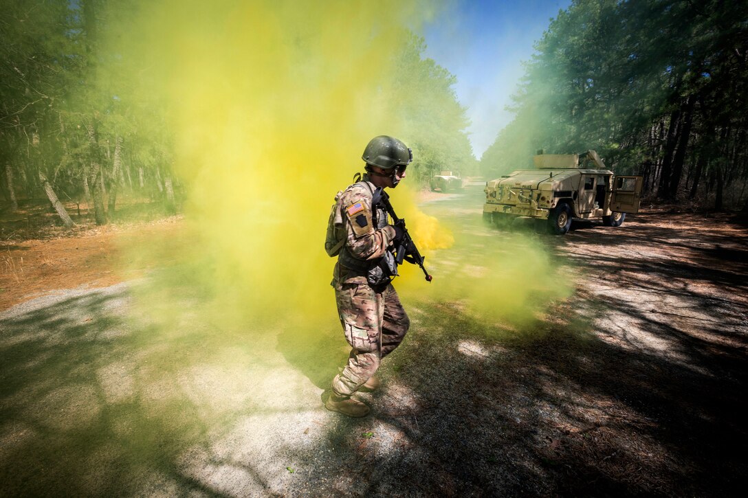 A soldier walks through yellow smoke.