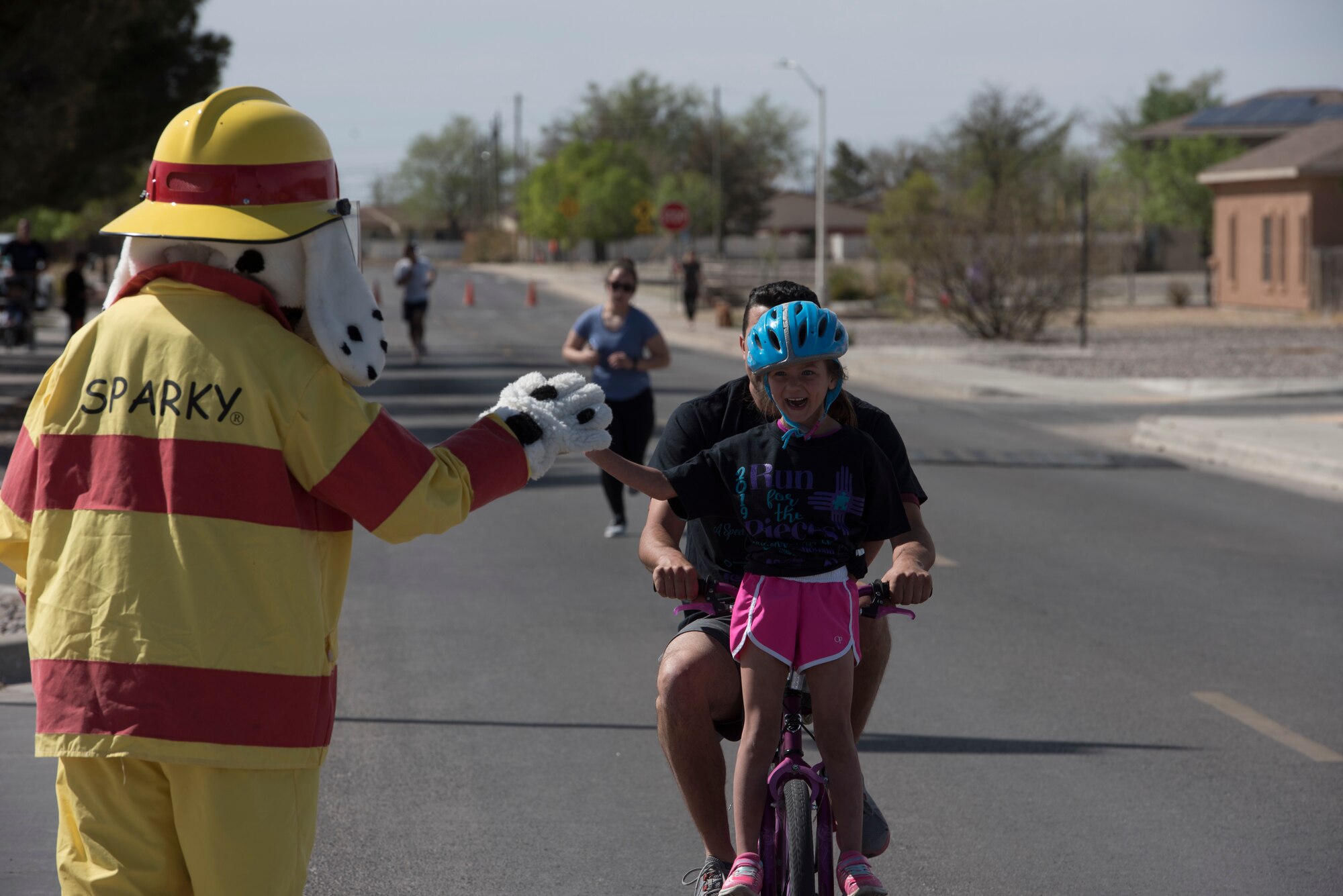 Sparky the Fire Dog gives a high five to an Autism Awareness fun run participant on Holloman Air Force Base, April 6, 2019. Over 750 people participated in the fun run and children’s carnival. (U.S. Air Force Photo by Staff Sgt. Timothy Young)