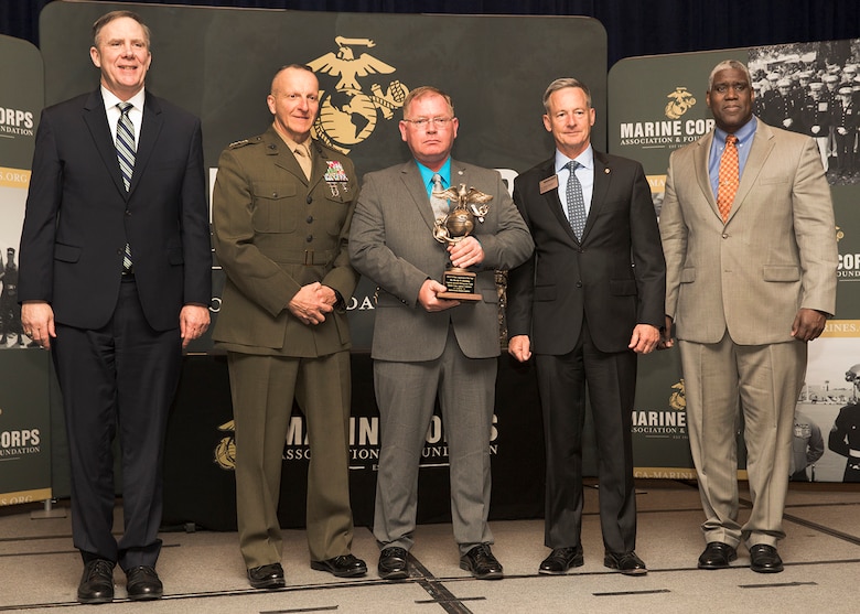 Harold W. Melching, center, branch head, Materiel Management Branch, Marine Corps Logistics Command, poses for a photo holding the 2018 Marine Corps Civilian Logistician of the Year Award he was awarded at the annual Marine Corps Association and Foundation Logistics Excellence Awards Dinner, March 28.