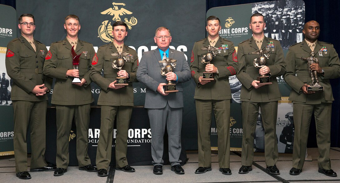Harold W. Melching, center, branch head, Materiel Management Branch, Marine Corps Logistics Command, poses for a photo holding the 2018 Marine Corps Civilian Logistician of the Year Award he was awarded at the annual Marine Corps Association and Foundation Logistics Excellence Awards Dinner, March 28.