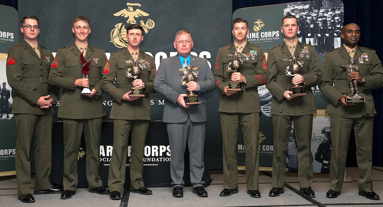 Harold W. Melching, center, branch head, Materiel Management Branch, Marine Corps Logistics Command, poses for a photo holding the 2018 Marine Corps Civilian Logistician of the Year Award he was awarded at the annual Marine Corps Association and Foundation Logistics Excellence Awards Dinner, March 28.