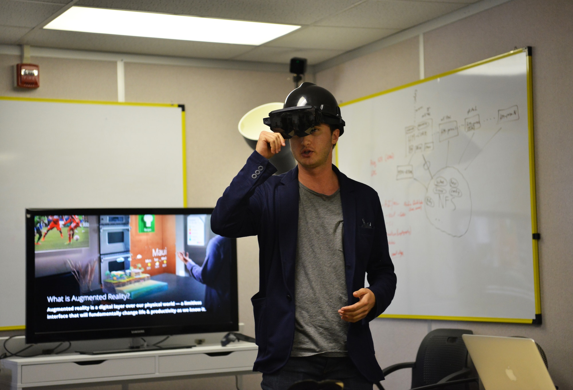 One of the innovating startup representatives wears a hard hat with see-through VR goggles that help to display a digital work center that can assist with working in a busy environment.