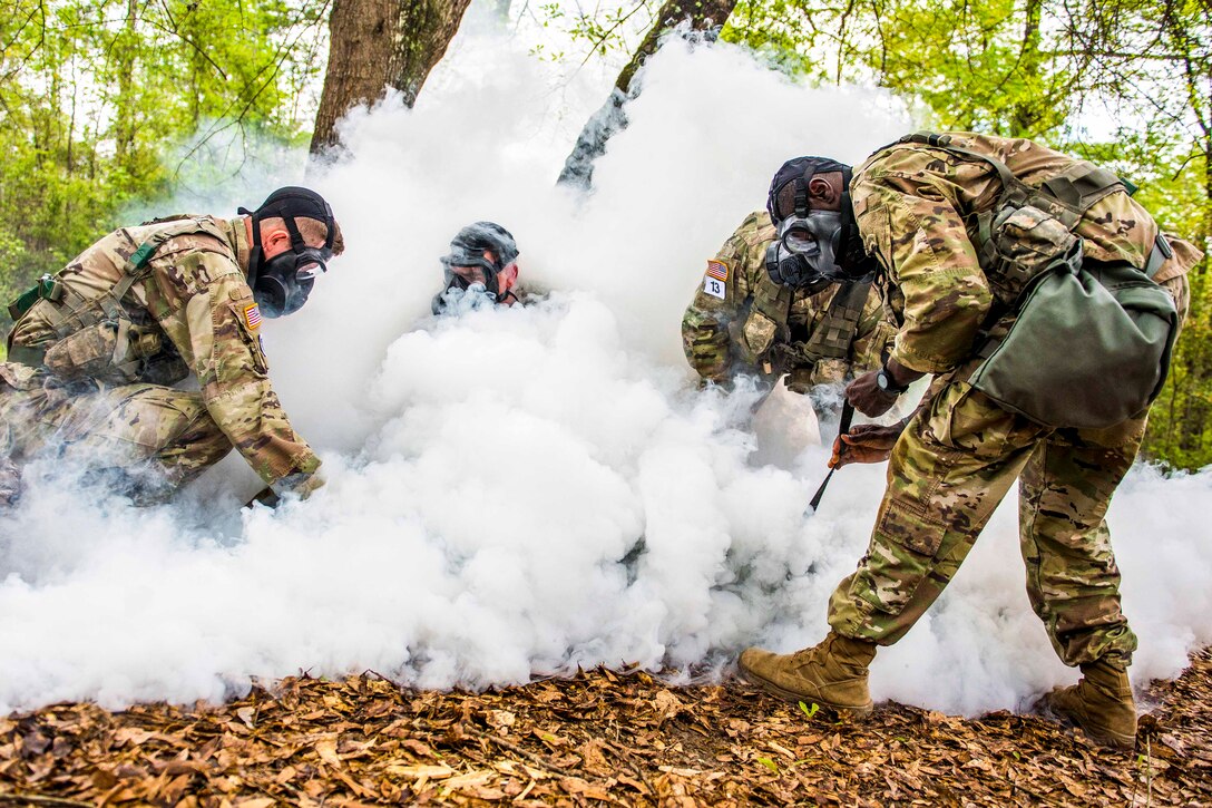 Four soldiers wearing gas masks surrounded by smoke.