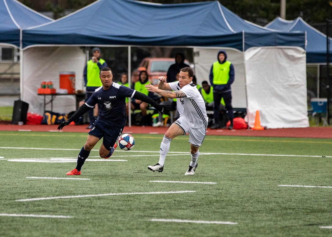 NAVAL STATION EVERETT, Wa. (April 16, 2019) - Petty Officer 2nd Class Devonte Ecford, stationed at Marine Corp Air Station Yuma, Az., from the Navy soccer team drives the ball passed Capt. Andrew Trahan, stationed at Fort Jackson, SC., from the Army soccer team during a second round match of the Armed Forces Sports Men’s Soccer Championship hosted at Naval Station Everett. (U.S. Navy Photo by Mass Communication Specialist 2nd Class Ian Carver/RELEASED).