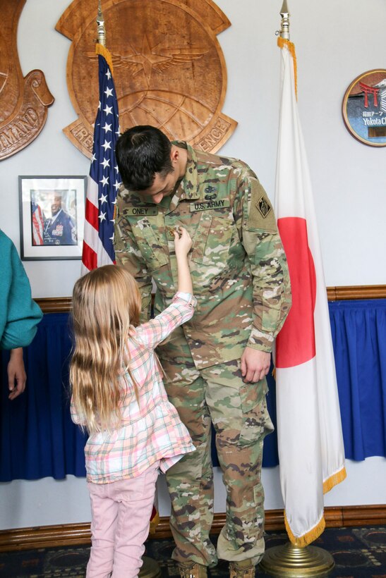 Military officer has his old rank replaced by his daughter during his promotion ceremony.