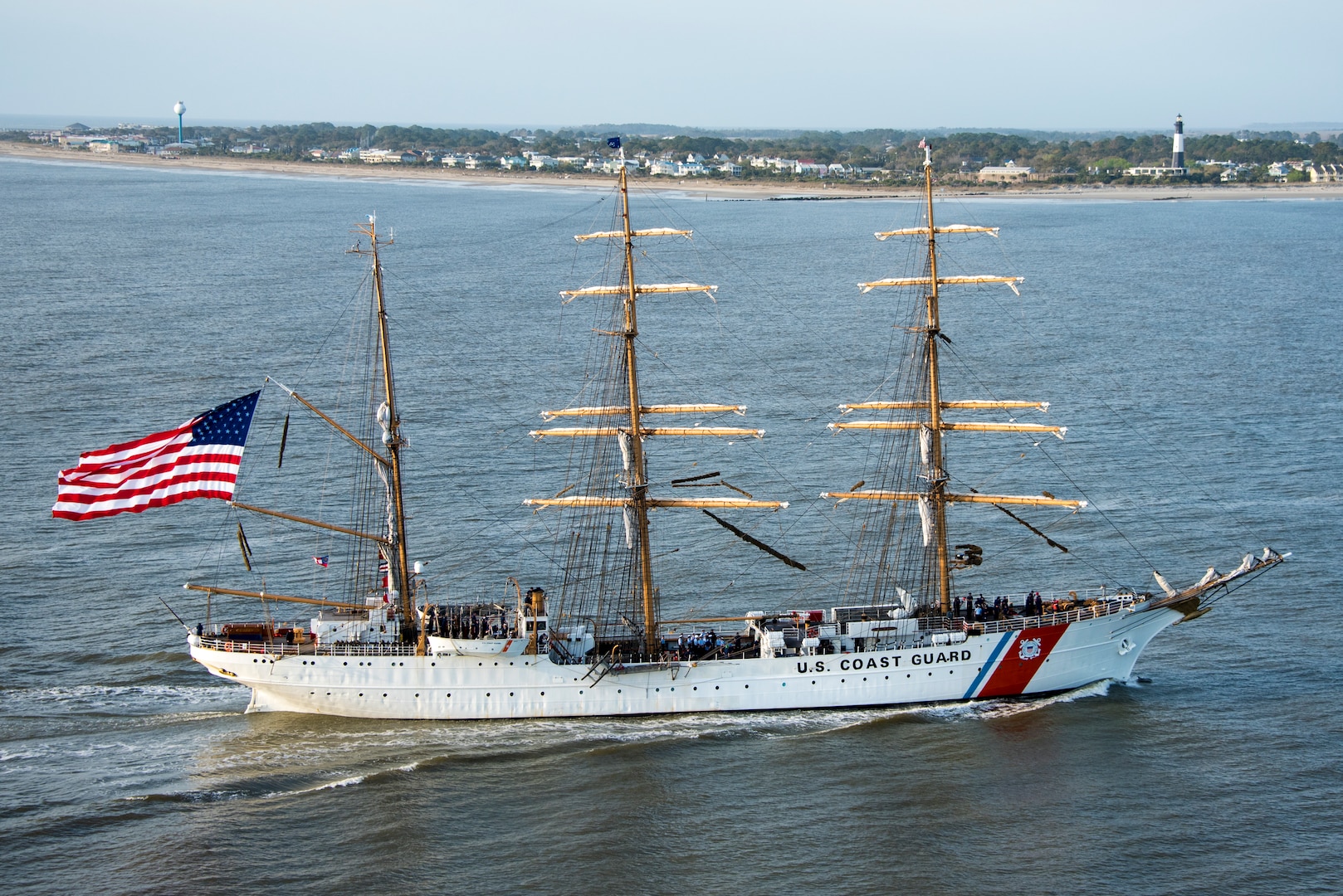 oast Guard Cutter Eagle transits down the Savannah River towards Savannah, Georgia, Mar. 15, 2019, in front of the Tybee Island Lighthouse. The Eagle arrived in Savannah for St. Patrick’s Day weekend with over 100 guests on board.