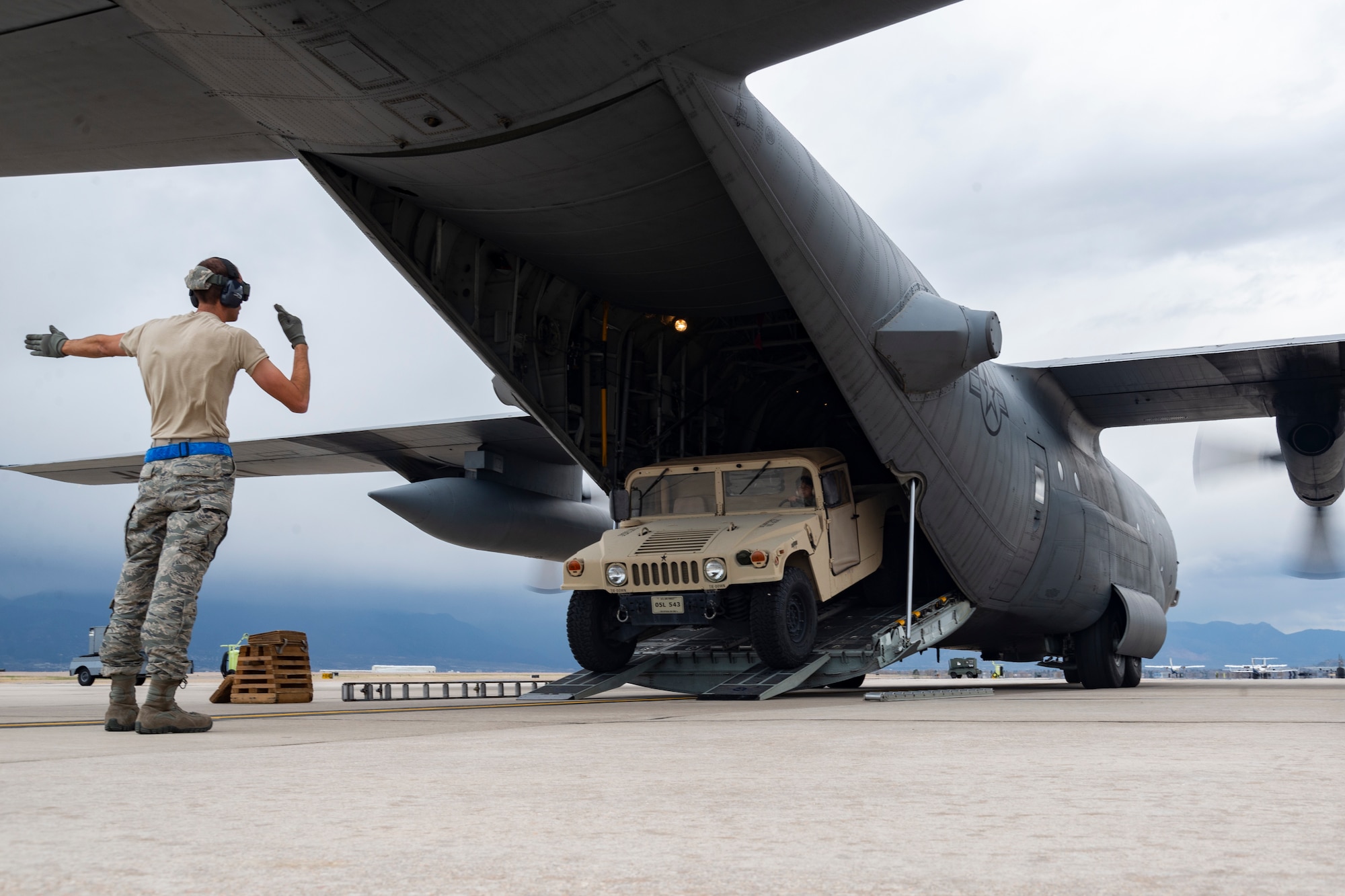 Tech. Sgt. Russell Hudson, a 39th Aerial Port Squadron air transportation technician, directs a vehicle as it is backed into a C-130 Hercules aircraft during an engine-running onload at Peterson Air Force Base, Colorado, April 17, 2019.