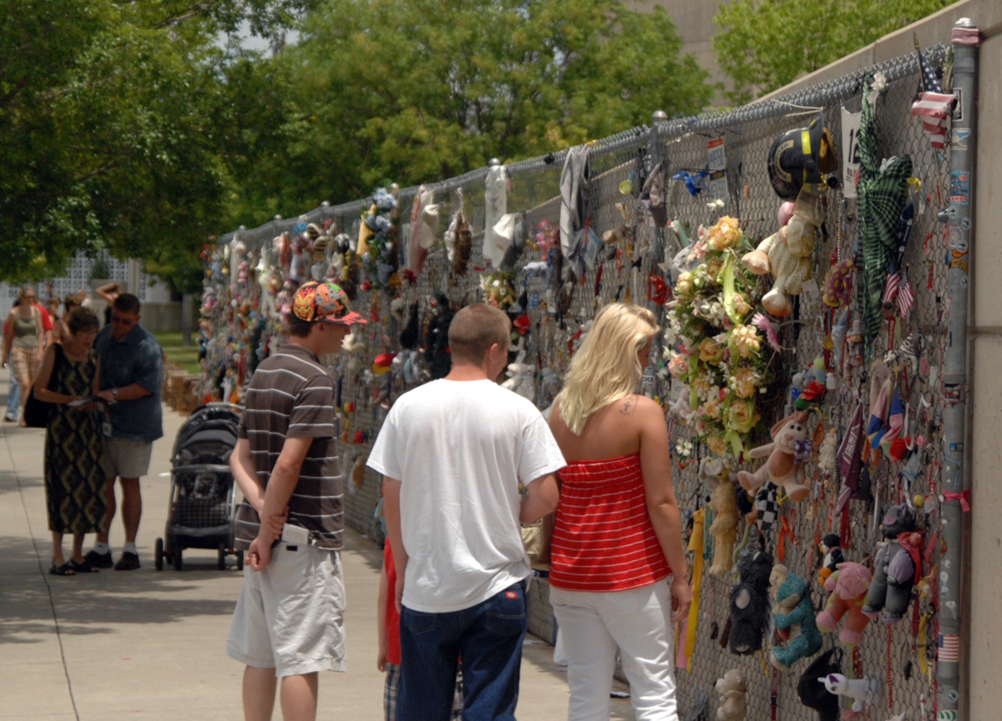 Visitors pay homage to the 168 victims of the April 19, 1995 bombing of the Alfred P. Murrah Federal Building in Oklahoma City, Okla. The memorial fence stretches more than 200 feet and is tribute which gives people the opportunity to leave tokens of remembrance. (U.S. Air Force photo)