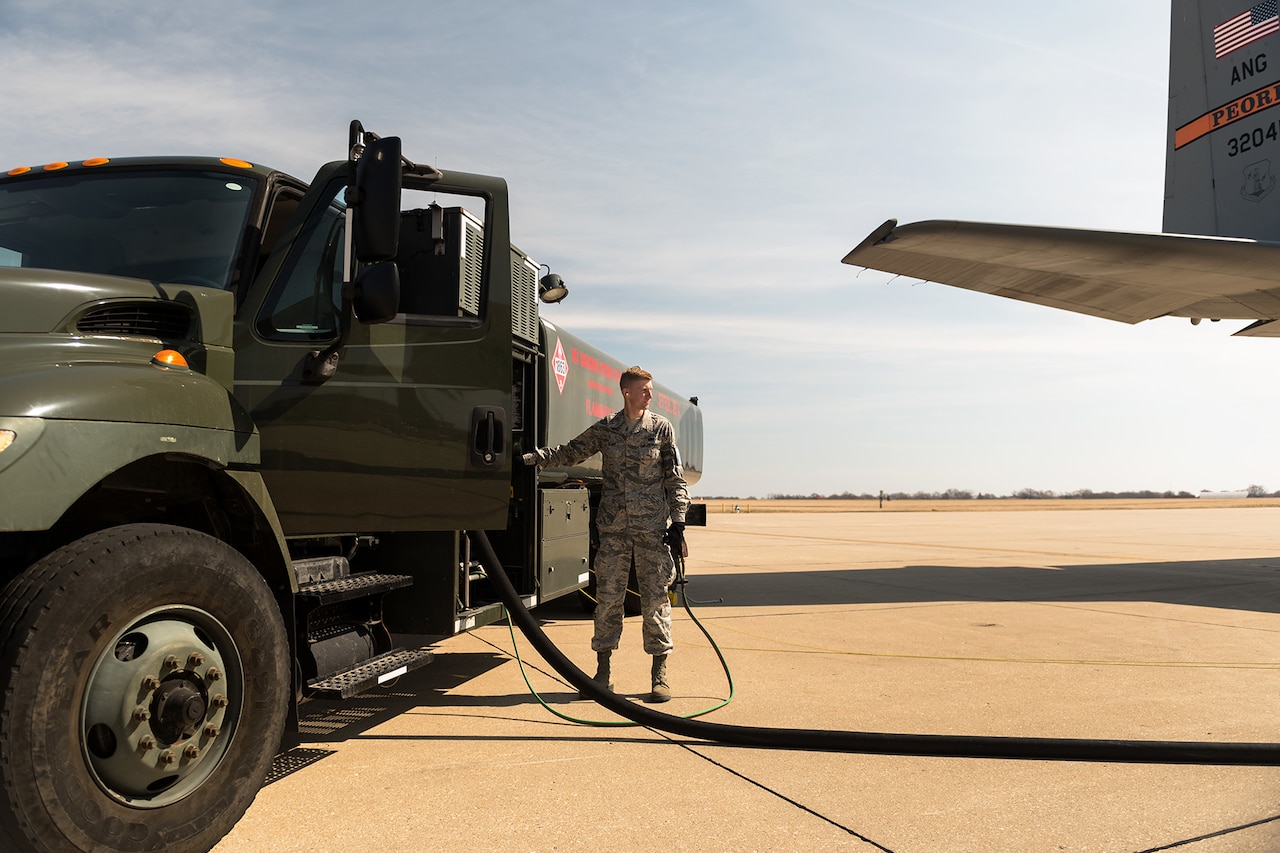A man operates fuel truck hose.