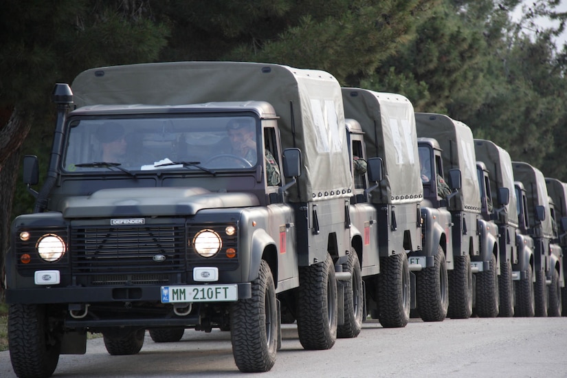 Albanian military vehicles travel in a convoy.