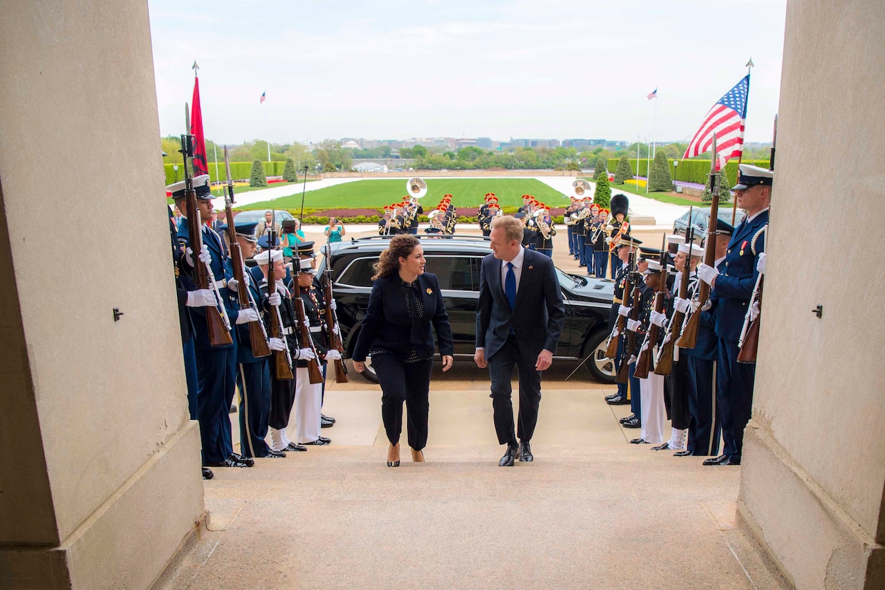 Acting Defense Secretary Patrick M. Shanahan walks up steps with the Albanian defense minister; service members stand on either side.