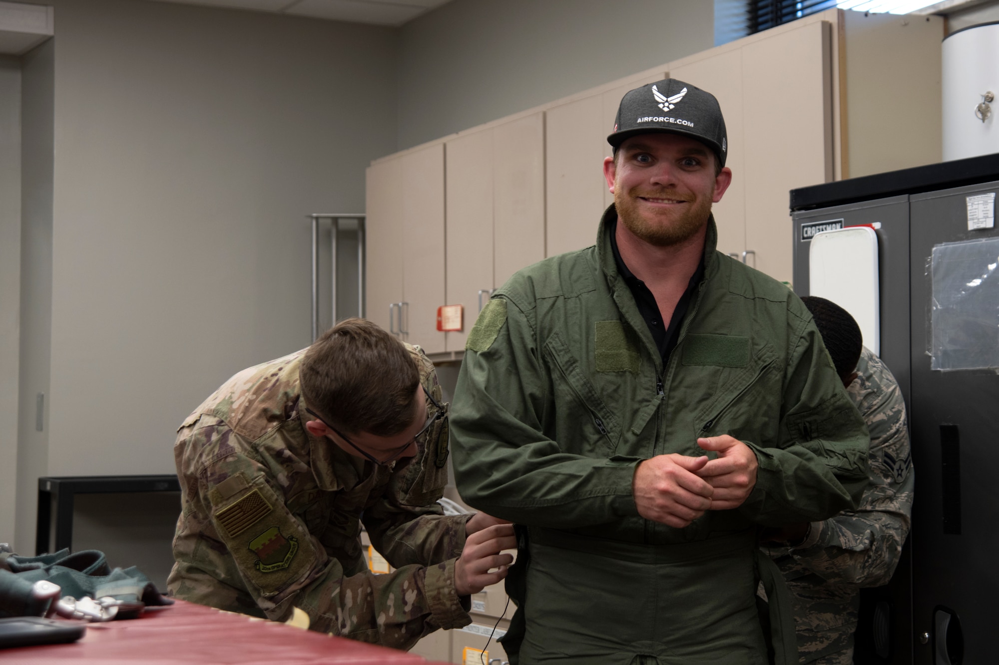 U.S. Air Force Senior Airman Matthew Day, left, and Airman 1st Class Orlando Harris, right, 20th Operations Support Squadron aircrew flight equipment technicians, adjust the fit of a G-suit worn by Conor Daly, Air Force Honda race car driver, at Shaw Air Force Base, S.C., April 15, 2019.