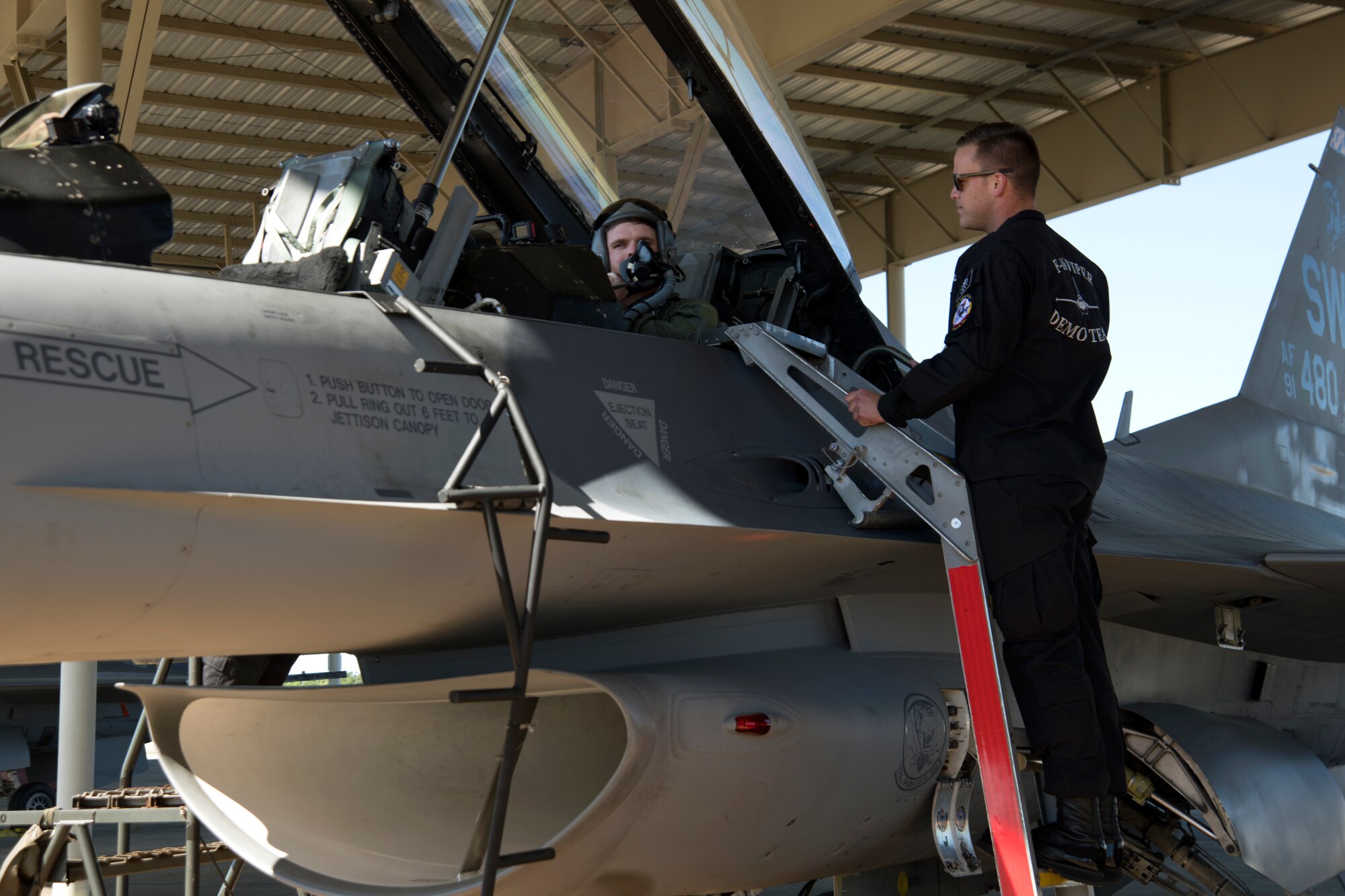 U.S. Air Force Staff Sgt. Trevor Griswold, F-16 Viper Demonstration Team electrical and environmental systems craftsman, stands by as Conor Daly, Air Force Honda race car driver, secures his helmet at Shaw Air Force Base, S.C., April 16, 2019.