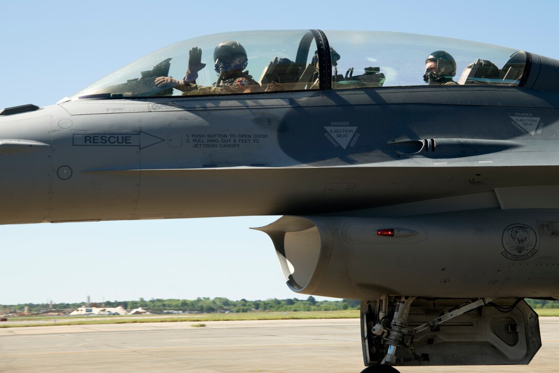 U.S. Air Force Maj. John Waters, F-16 Viper Demonstration Team commander and pilot, waves while taxiing his F-16D Viper with Conor Daly, Air Force Honda race car driver, at Shaw Air Force Base, S.C., April 16, 2019.