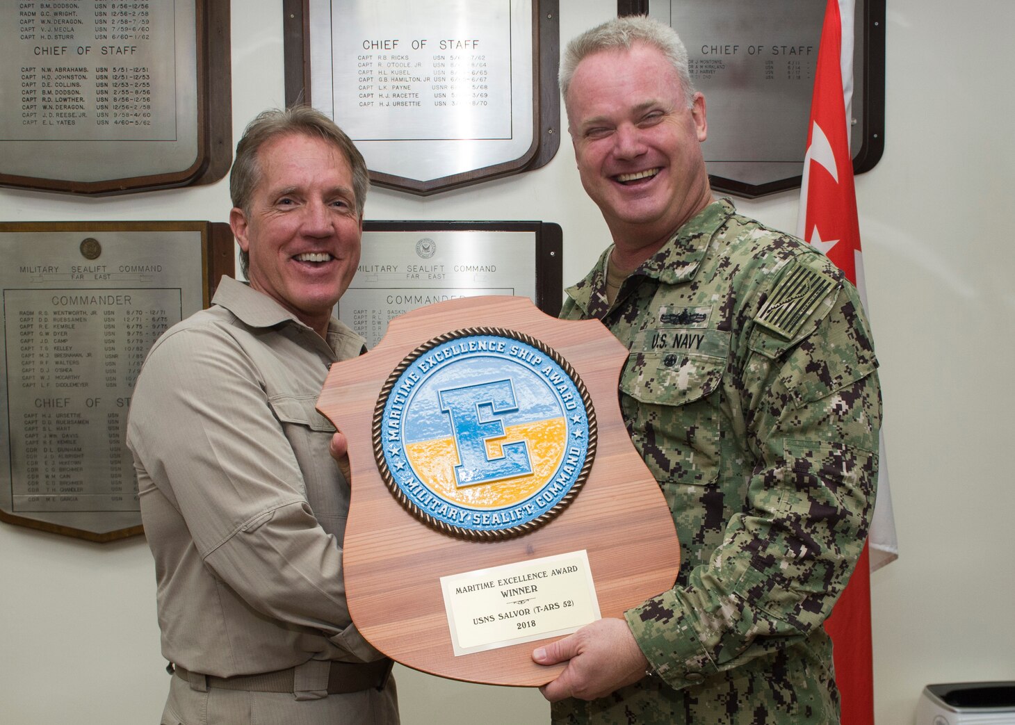 Military Sealift Command (MSC) Capt. Peter Lenardson, master aboard the rescue and salvage ship USNS Salvor (T-ARS 52), left, accepts the 2018 MSC Maritime Excellence Award from U.S. Navy Capt. Robert Williams, commodore, MSC Far East, at MSC Far East headquarters. The Maritime ‘E’ is presented annually to government owned and operated ships for attaining the highest standards of readiness. Salvor regularly conducts salvage, diving, towing, offshore firefighting, heavy-lift operations and theater-security cooperation missions. It is one of only two rescue and salvage vessels in the MSC inventory, and the only ship of its kind in the Far East.