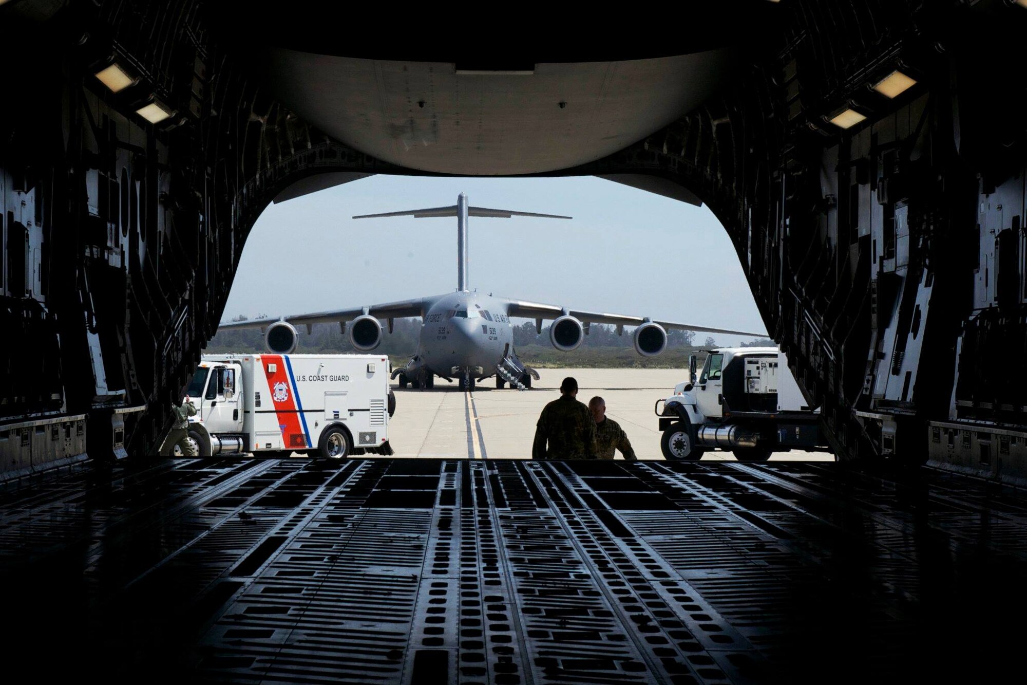An Air Force C-17 and Coast Guard vehicle can be seen through the cargo bay of another Air Force C-17.